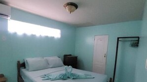 Een slaapkamer met een bed, een nachtkastje, een raam met gordijnen en een deur.