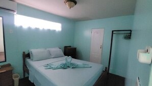 Un dormitorio con cama, mesita de noche, repisa y una puerta.