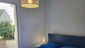 Un dormitorio con una cama grande, una mesita de noche, una lámpara y vistas al exterior.