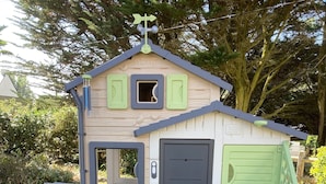 Una casita de madera con puerta, ventana y un banco.