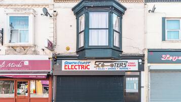 A corner building with a bay window, a closed shuttered shop, and a sign for 'South Coast Electric'.