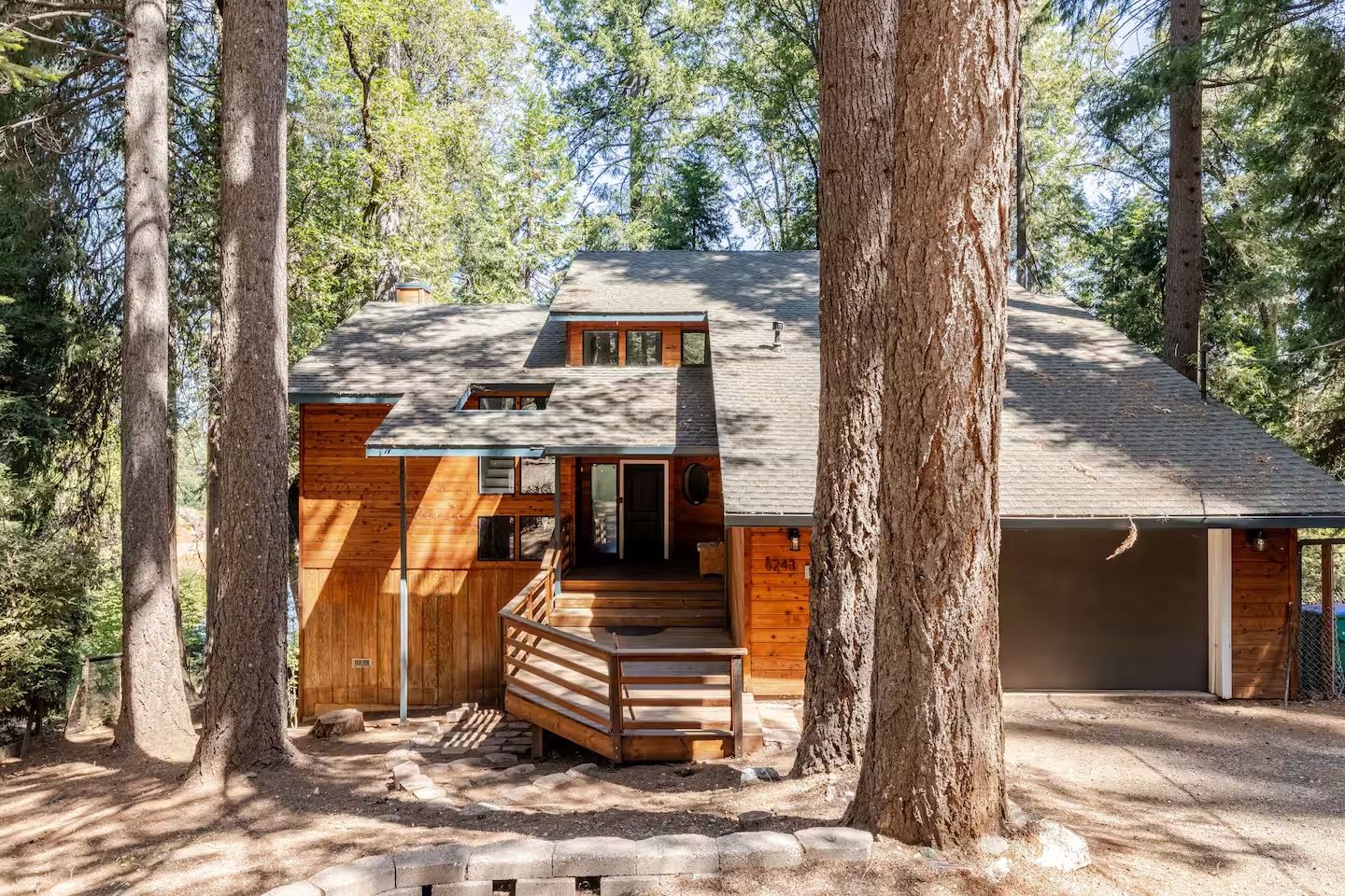 A two-story cabin with a wooden exterior, a front porch, and a garage.