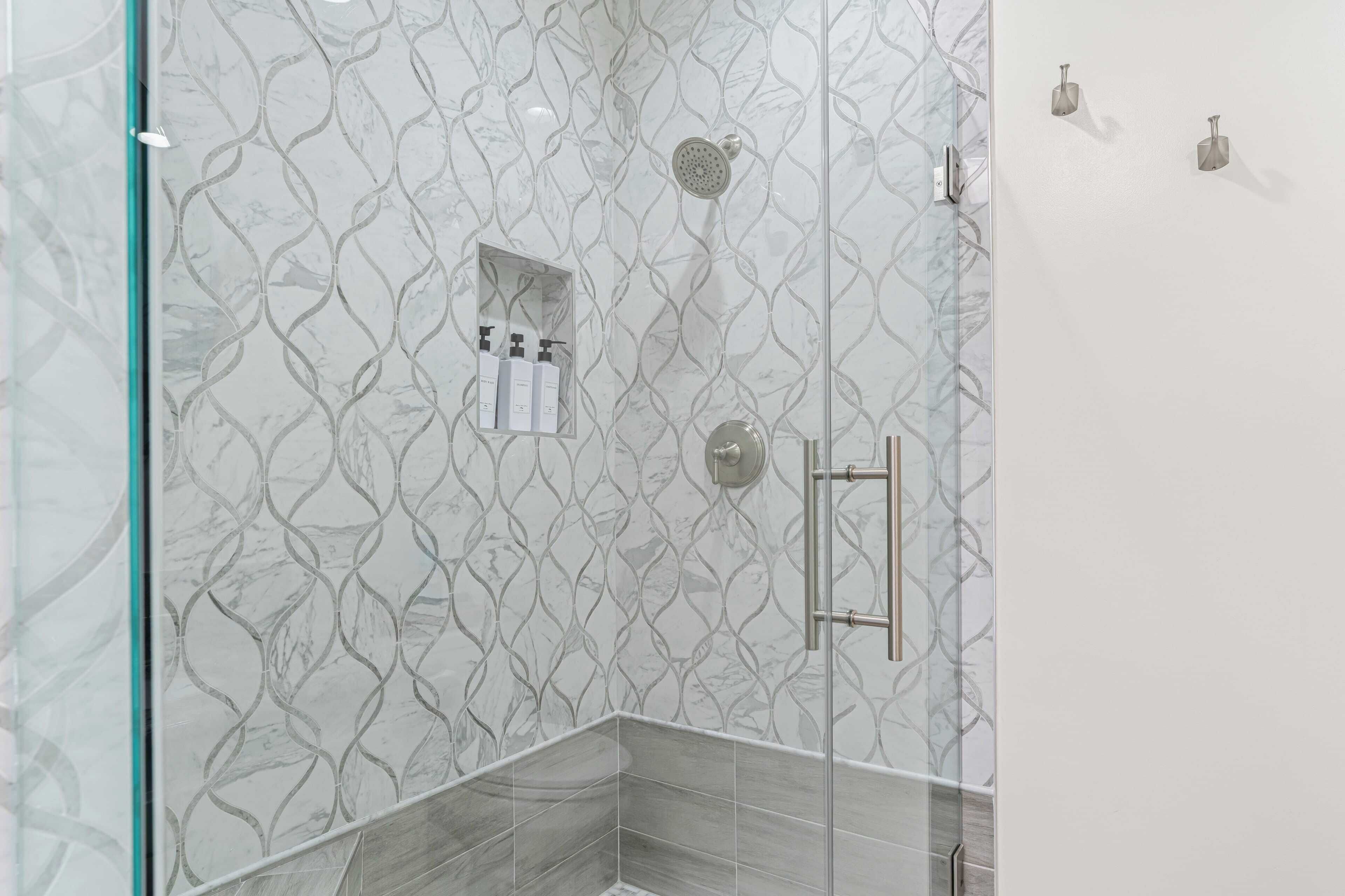 A shower area with a patterned wall, a glass door, and a towel rack.