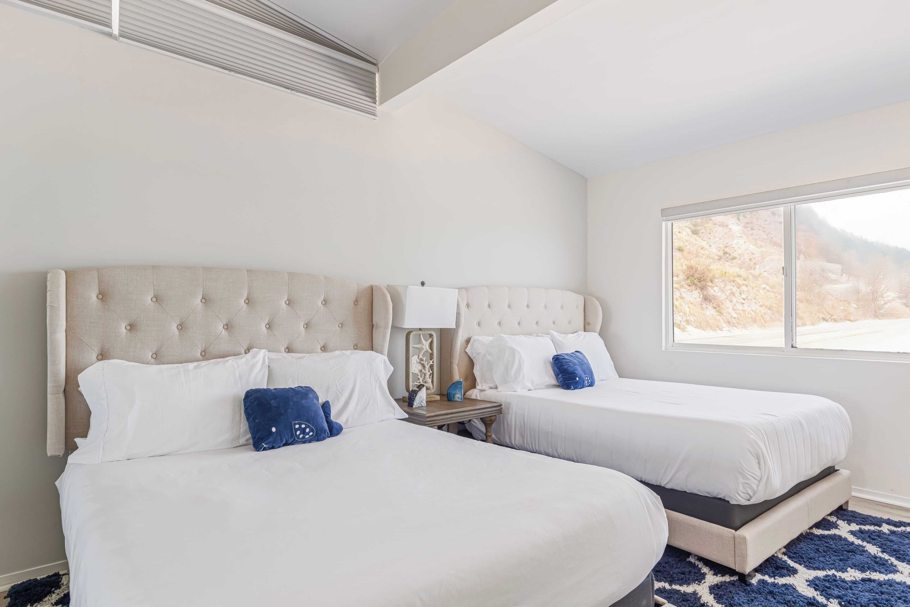Une chambre d’hôtel avec deux lits, une grande fenêtre et une vue sur l’extérieur.