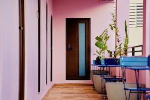 Un pasillo con una puerta, piso de baldosas y una planta.