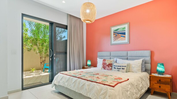 A bedroom with a large bed, a sliding glass door to a balcony, a ceiling light, and a framed picture on the wall. - 1BR 1BA Condo w Pool/Jacuzzi/Gym (Noord)