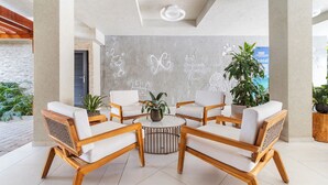 A modern lounge area with wooden furniture, a central round table, and decorative wall art. - 1BR 1BA Condo w Pool/Jacuzzi/Gym (Noord)