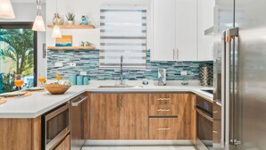 A modern kitchen with wooden cabinets, a stainless steel refrigerator, and a tiled backsplash. - 1BR 1BA Condo w Pool/Jacuzzi/Gym (Noord)