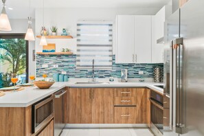 A modern kitchen with wooden cabinets, a stainless steel refrigerator, and a tiled backsplash. - 1BR 1BA Condo w Pool/Jacuzzi/Gym (Noord)
