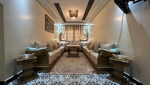A spacious living room with a central sofa set, patterned rug, and decorative lighting. - Kasbah Itran Appart (Sti Fadma)