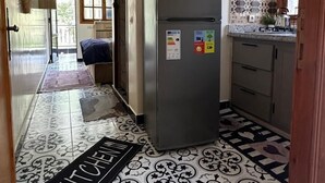 A kitchen with a refrigerator, tiled floor, and a kitchen mat. - Kasbah Itran Appart (Sti Fadma)