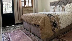 A bedroom with a bed, a window, a door, and a headboard. - Kasbah Itran Appart (Sti Fadma)