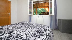 Een slaapkamer met een bed, een raam met gordijnen, een radiator en een houten deur.