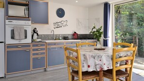Een moderne keuken met een klok, een eettafel met stoelen en uitzicht op groen.