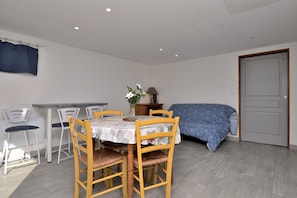 A room with a dining table, chairs, a bed, a door, and a window with curtains. - Holiday Home 'Au Fil De L'eau' with Mountain View, Private Terrace and Wi-Fi (Chein Dessus)