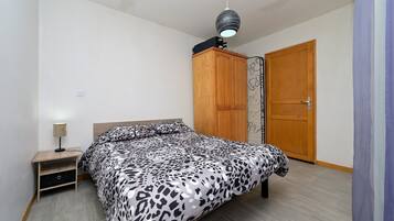 A bedroom with a bed, a wardrobe, a nightstand, and a ceiling light fixture.