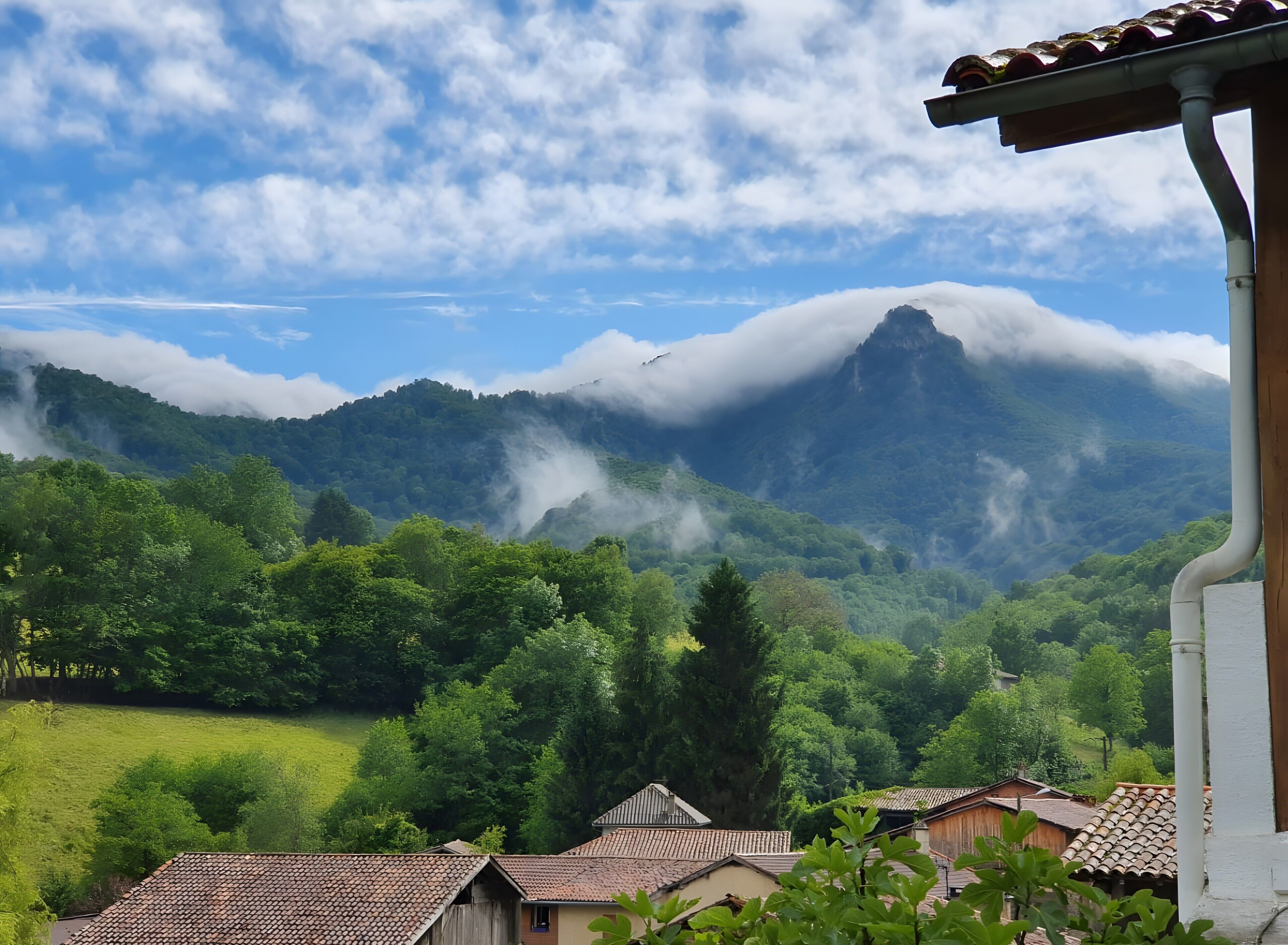 A mountainous landscape with a village in the foreground, featuring traditional buildings with tiled roofs.