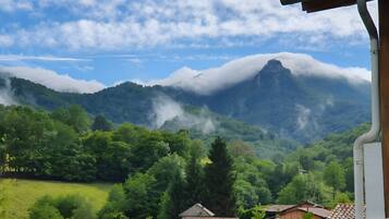 A mountainous landscape with a village in the foreground, featuring traditional buildings with tiled roofs.