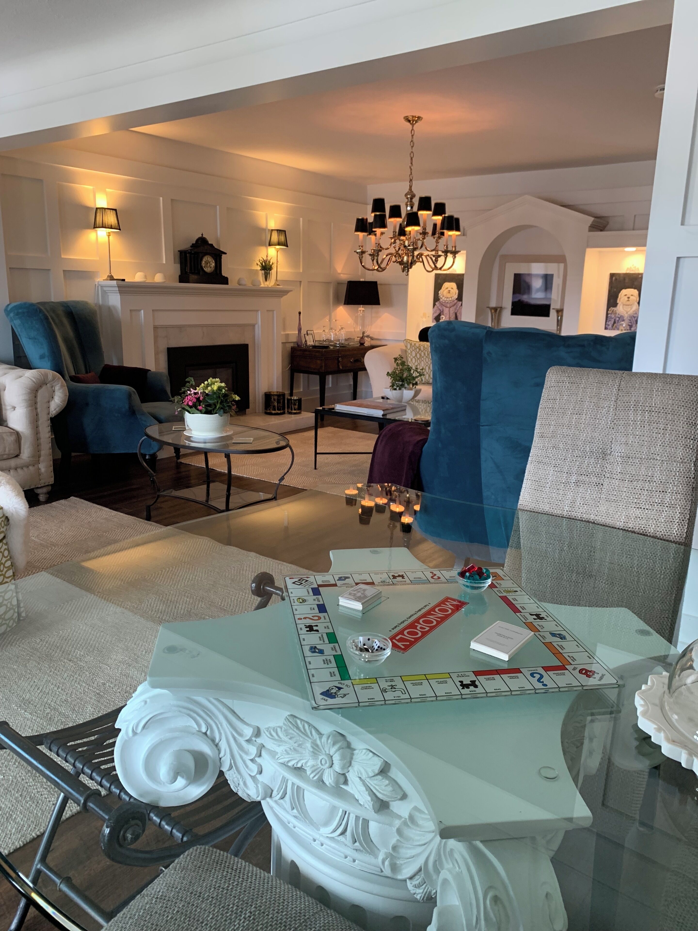 A living room with a fireplace, a chandelier, and a board game on a glass table.