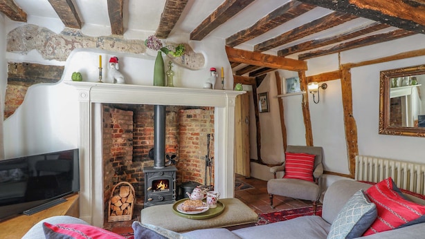 A cozy living room with a fireplace, a sofa, and a television. - Bank House (Norwich)