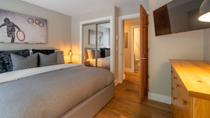 Une chambre à coucher avec un lit, une table de chevet, une lampe et un tableau représentant les anneaux olympiques.