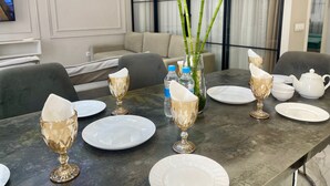 A dining table set with crystal goblets, plates, and a white teapot, with a vase of green bamboo stalks in the center. - Boulevard steak house (Tashkent)
