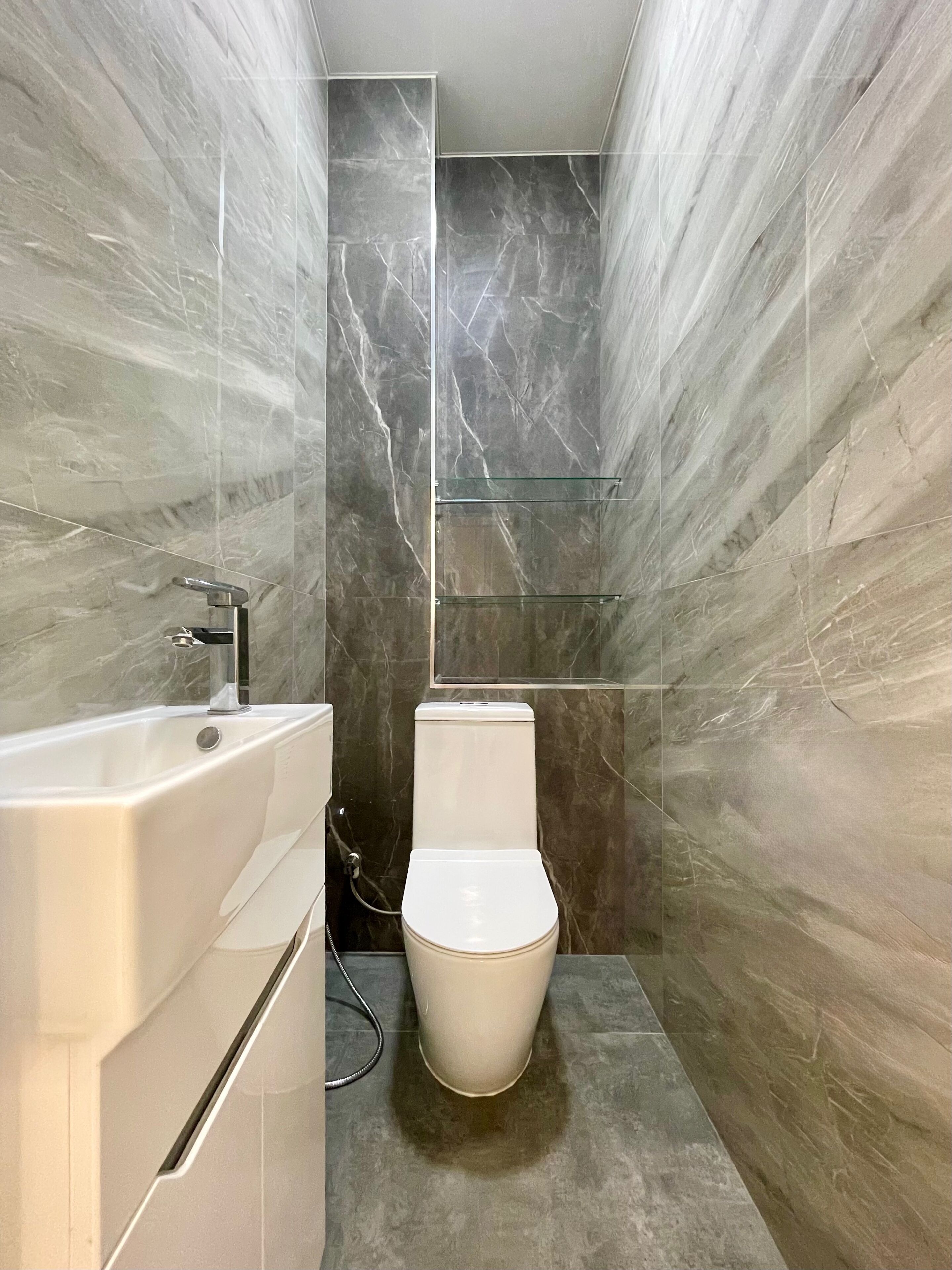 A modern bathroom with a bathtub, toilet, and glass shower enclosure.