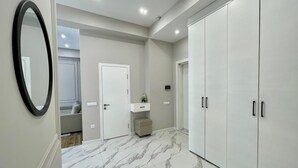 A hallway with a marble floor, a white door, a small vanity with a mirror, and a wardrobe with black handles. - Boulevard steak house (Tashkent)