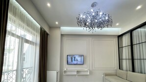 A modern living room with a large sofa, a television mounted on the wall, and a chandelier. - Boulevard steak house (Tashkent)