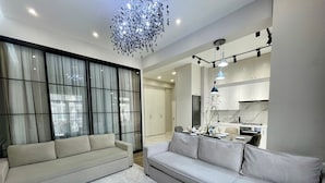 A modern living room with a sofa set, a dining area with a table set for four, and a kitchen with white cabinets and a marble backsplash. - Boulevard steak house (Tashkent)