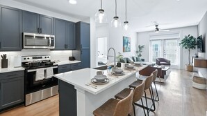 A modern kitchen with grey cabinets, a stainless steel oven, and a central island with bar stools.
