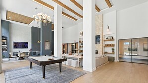 A modern living room with a pool table, a TV, and a cozy seating area.