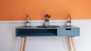 A desk with a mirror, two potted plants, and a gray rug.