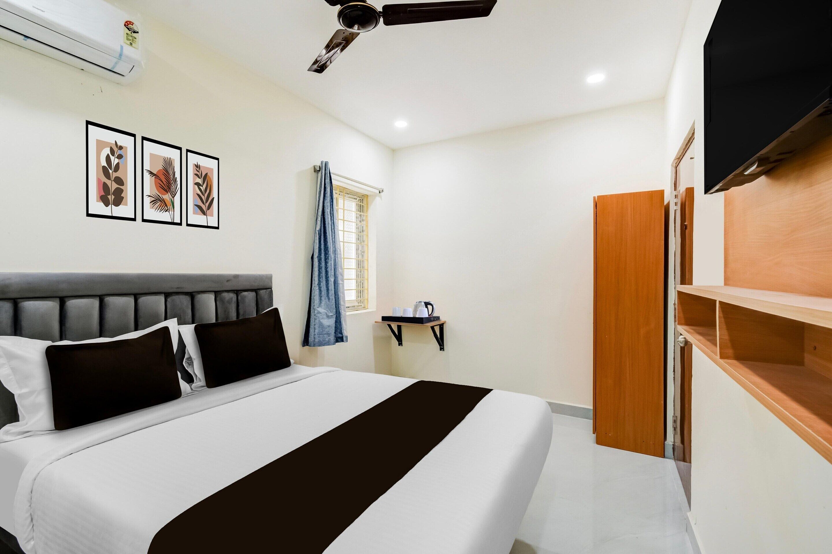 A bedroom with a bed, a ceiling fan, a mounted TV, and a window with a curtain.