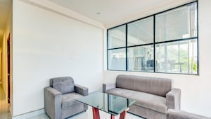 Ein modernes Wohnzimmer mit einem Glastisch, zwei grauen Sofas und einem großen Fenster.