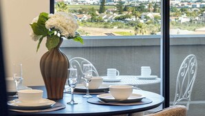 A dining table with chairs, a vase with flowers, and a view of a mountain and town. - 2 Bedroom, Mountain View Penthouse, Century City (Cape Town)