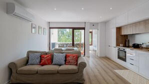 A modern living room with a sofa, a dining area, and a kitchen with wooden cabinets.