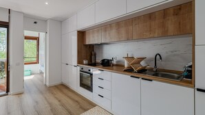 A modern kitchen with white cabinets, a wooden countertop, a built-in oven, and a large window.