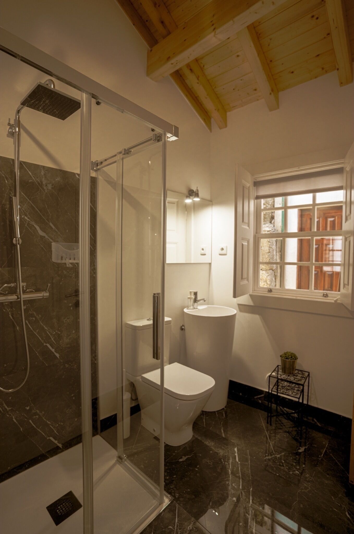 Un baño moderno con ducha de vidrio, inodoro blanco y lavamanos.