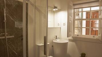 Un baño moderno con ducha de vidrio, inodoro blanco y lavamanos.