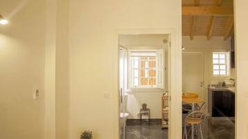 A spacious room with a wooden floor, a small table with chairs, and a window with a view of the outside.