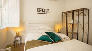 A hotel room with a bed, bedside tables, a wardrobe, and a wall-mounted air conditioner. - Alojamento 5 Outubro (Amarante)