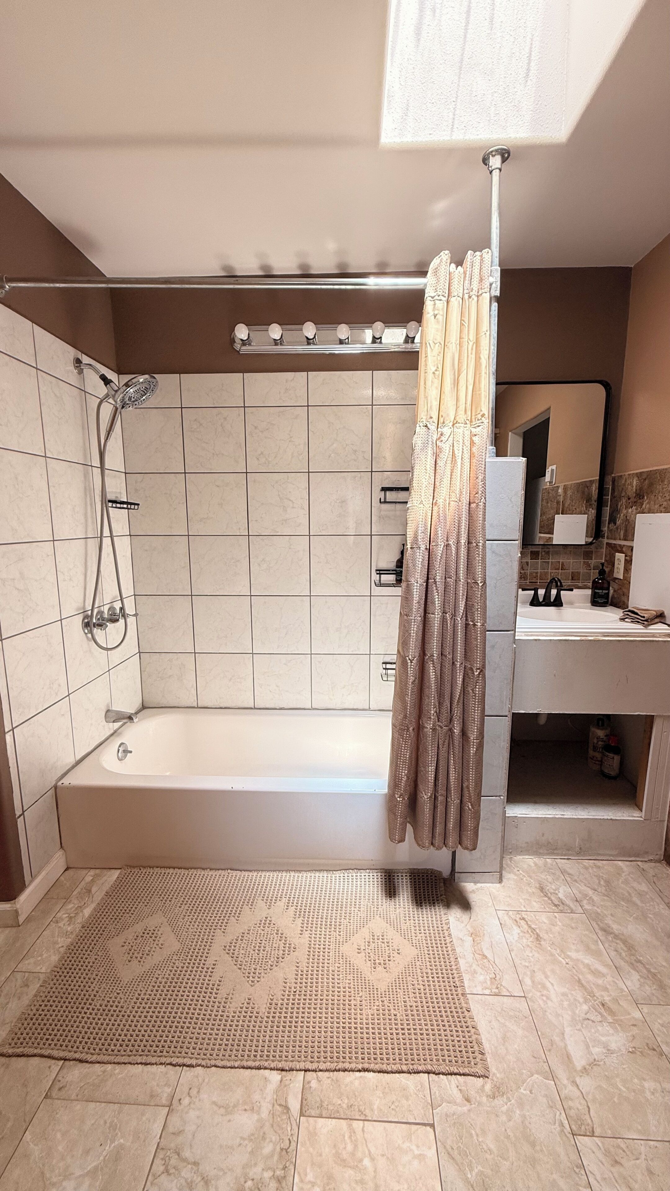 A modern bathroom with a walk-in shower, a bathtub, a vanity with a mirror, and a shower curtain.
