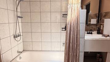 A modern bathroom with a walk-in shower, a bathtub, a vanity with a mirror, and a shower curtain.