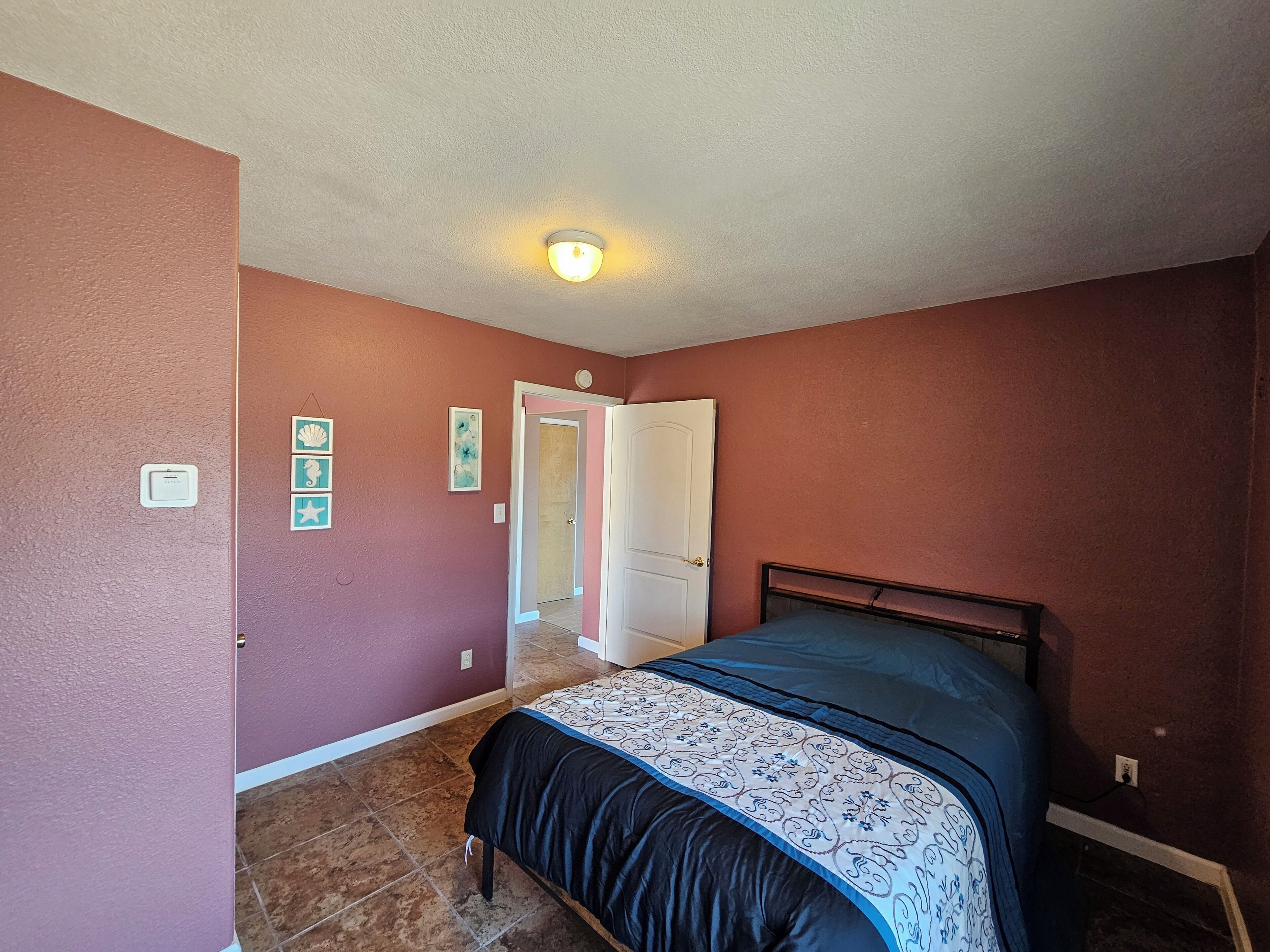 Um quarto com uma cama, uma porta e um luminário.