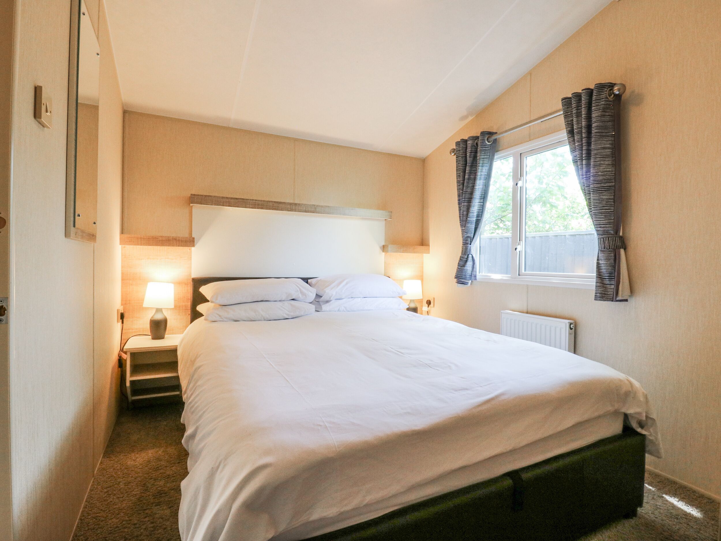 A neatly made bed with white linens in a hotel room.