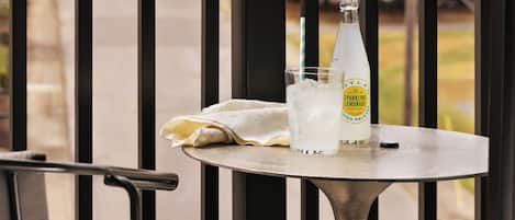 Une table avec une bouteille de limonade pétillante, un verre rempli de glaçons et une paille rayée.