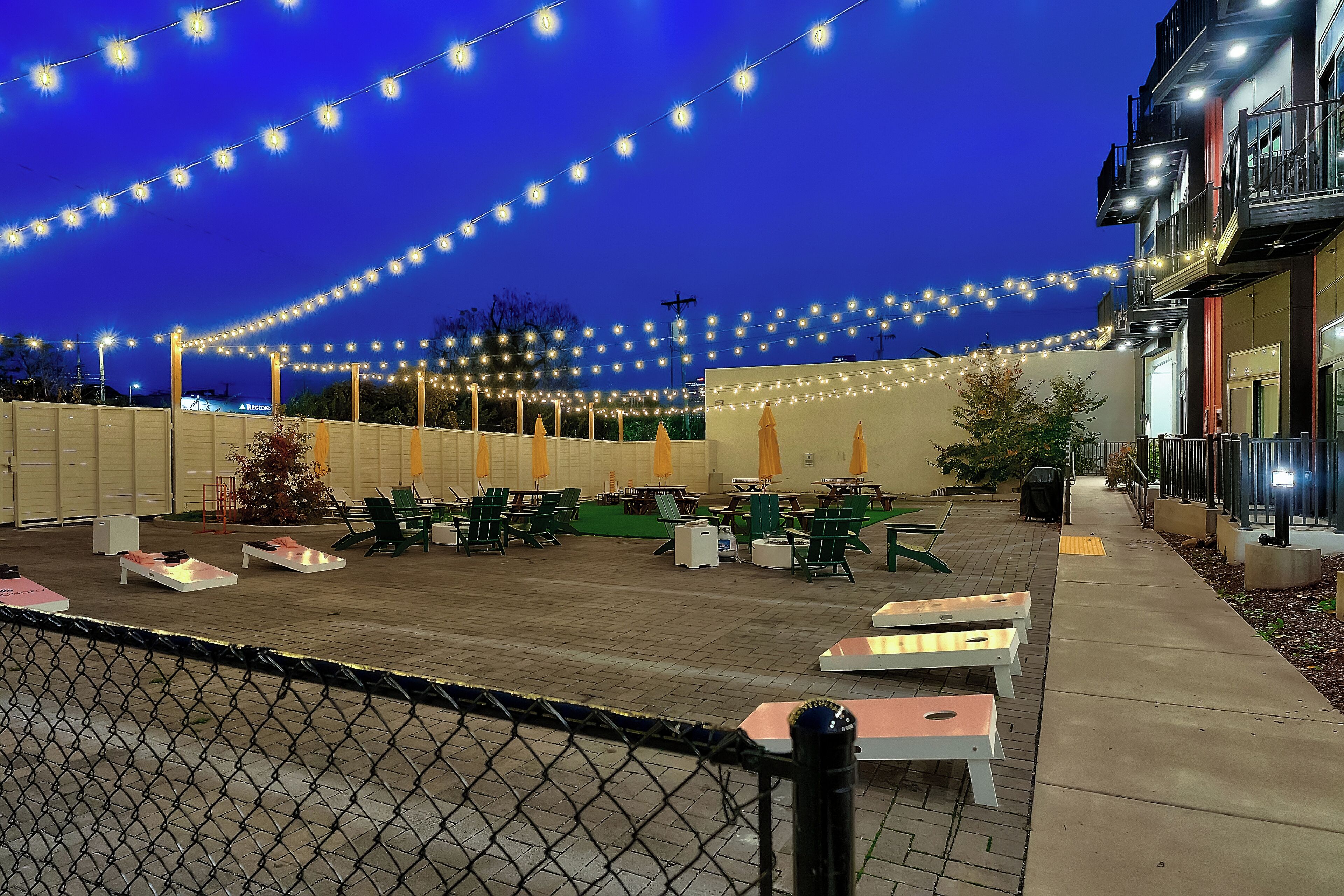 An outdoor patio area with string lights, tables, and chairs.