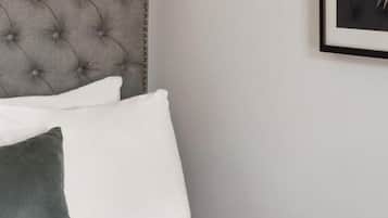 Una cama bien hecha con cabecera capitonada, almohadas blancas y verdes, y una revista sobre la cama.