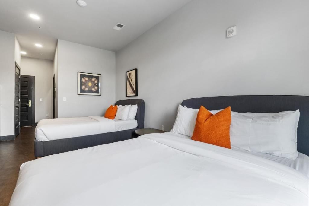 Una camera d'albergo con due letti singoli e un letto matrimoniale, oltre a un comodino.